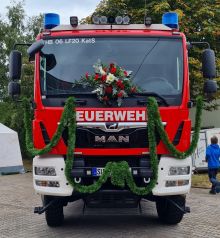 Frontansicht des mit einem Gesteck geschmückten Löschgruppenfahrzeugs.