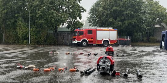 Eine tragbare Feuerlöschkreiselpumpe und feuerwehrtechnische Ausrüstung stehen im Regen.