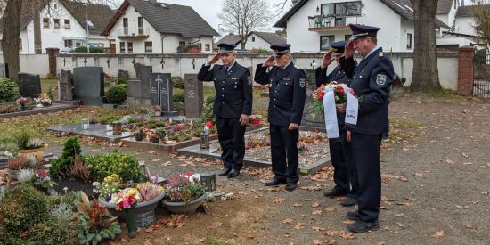 Vier Feuerwehrmänner salutieren vor einem Grab.